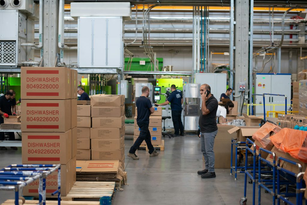 A photo os the inside of a warehouse with people moving merchandise around.